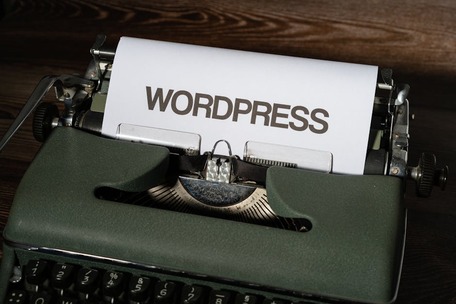 A sheet of paper with the word "WORDPRESS" typed on it is loaded in a vintage green typewriter on a wooden surface.