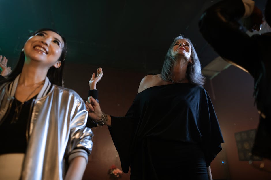 Three people are standing indoors, smiling and looking upward, appearing to enjoy themselves at an event or gathering.