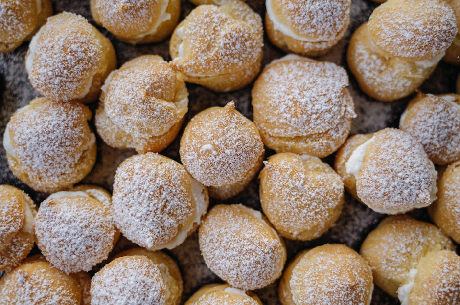 A close-up view of multiple cream puffs topped with powdered sugar, arranged closely together.