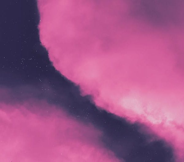 The image shows a night sky with the moon visible in the top left corner, scattered stars, and large clouds tinted pink.